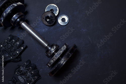 old dumbbell with gloves dark background with empty space minimal style,sports equipment