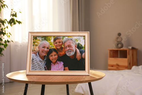 Framed family photo on wooden table in bedroom