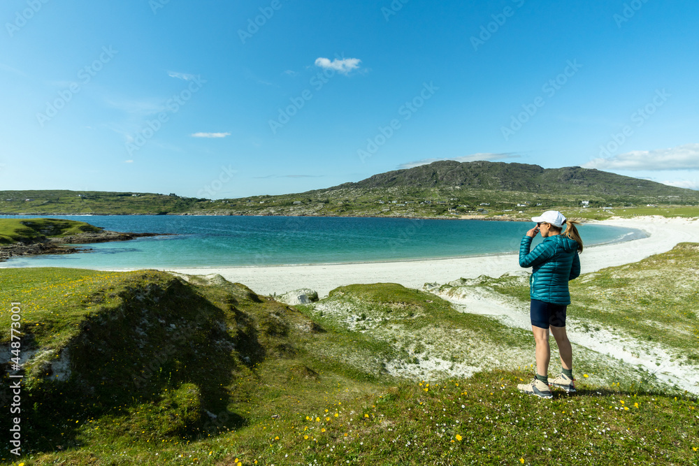 A female traveler admiring the scenery on Dog's Bay beach in Galway Ireland