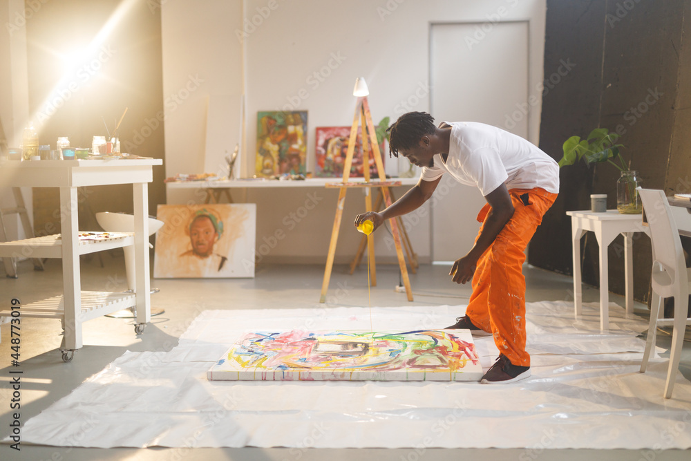 Fototapeta premium African american male painter at work painting on canvas in art studio