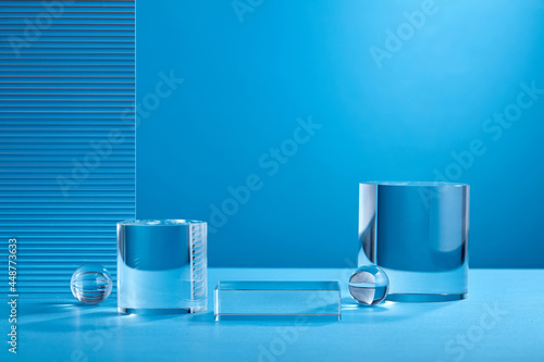 Glass podium minimal scene with glass geometric platform with ribbed acrylic plate on a blue background. Stand to show cosmetic product. Stage showcase on glass pedestal modern studio blue color