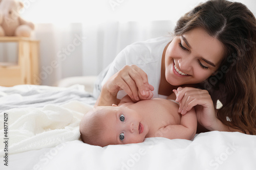 Happy young mother with her cute baby on bed at home