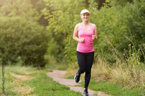 Pretty sporty woman jogging at park © Angelov