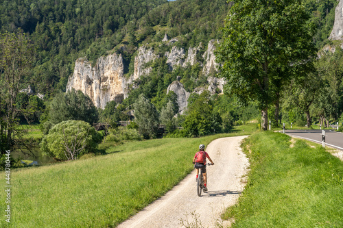 beautiful active senior woman cycling with her electric mountain bike in the rocky Upper Danube Valley on the Swabian Alb between Beuron and Sigmaringen