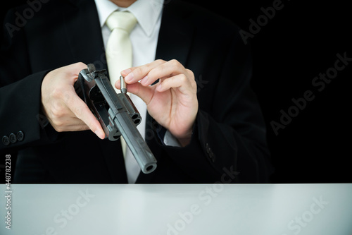 Unrecognizable Asian businessman loading an ammunition into revolver gun.