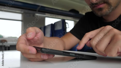 Male hands using the phone in the train. Bearded middle aged man looking at smartphone photo