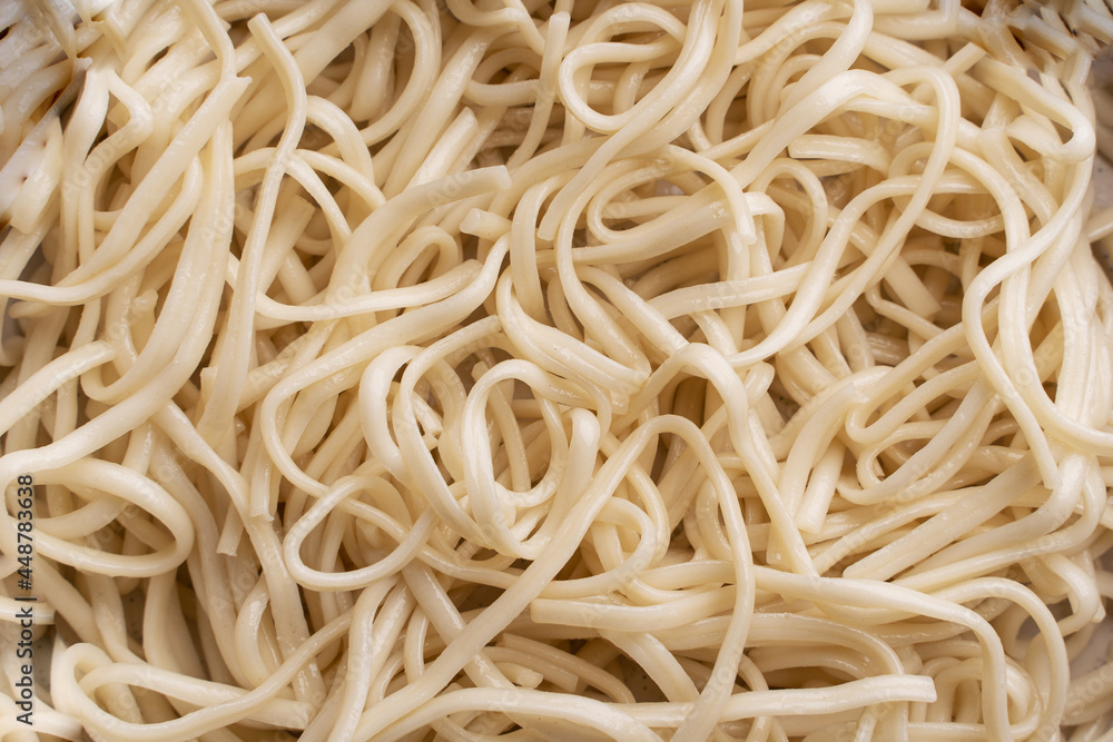 The texture of udon noodles. White noodles are visible throughout the frame. An ingredient for making a wok. Asian food. Asian pasta. Cooking food. Strid food. Gluten-free fries. 