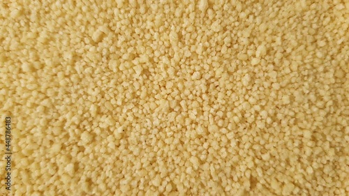 Close up of yellow golden dry couscous top view from above. Macro food us a background with copy space from above. Nutrition vegan vegetarian ingredient concept.