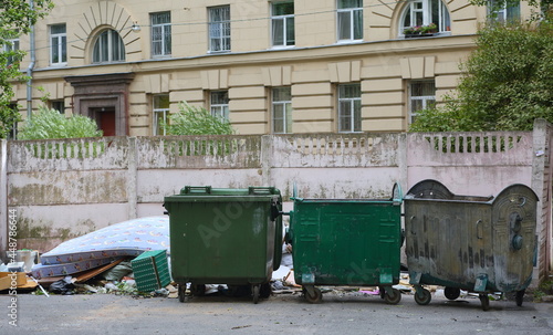 Three small green plastic mobile garbage containers on the street