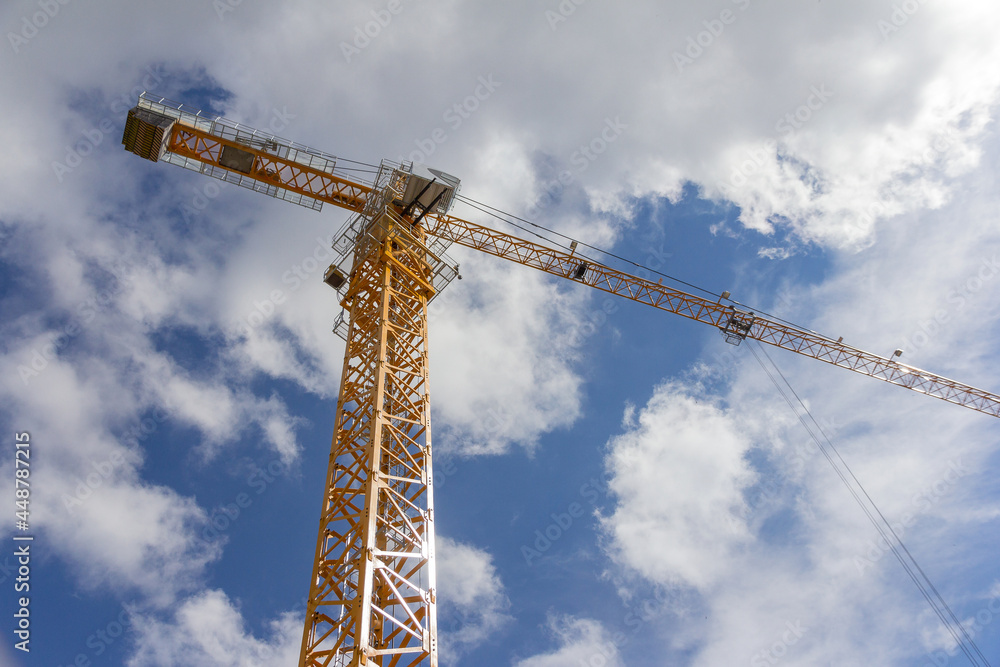 Construction crane against the blue sky. Beige crane at the construction site. Construction crane against the blue sky. Beige crane at the construction site.