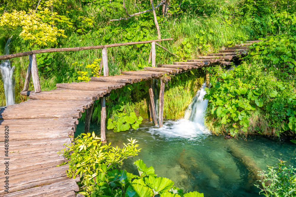 Wooden footpath at Plitvice national park, Croatia. Pathway in the forest near the lake and waterfall. Fresh beautiful nature, peaceful place. Famous tourist destination. Wooden footpath at Plitvice national park, Croatia. Pathway in the forest near the lake and waterfall. Fresh beautiful nature, peaceful place. Famous tourist destination.