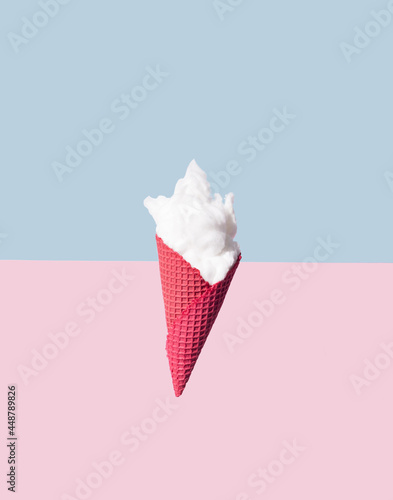 Red ice cream cone and white fluffy cotton wool on pastel blue and pink background. Minimal  summer concept.