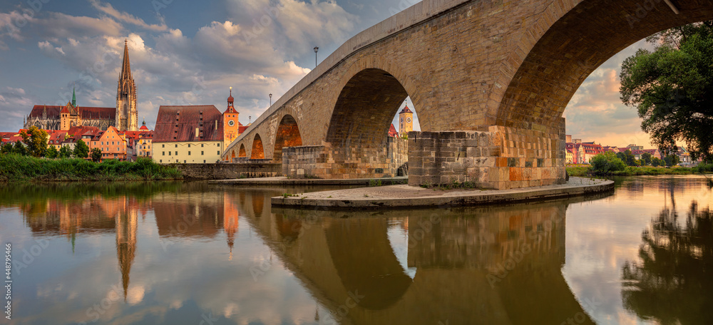 Regensburg, Germany. Cityscape panoramic image of Regensburg, Germany with Old Stone Bridge over Danube River and St. Peter Cathedral at summer sunset.