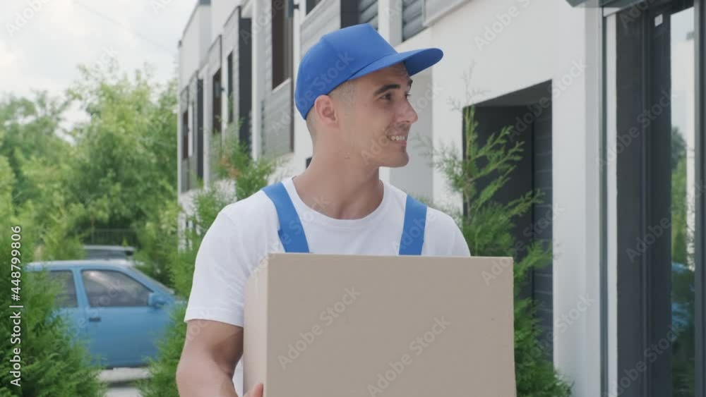 Young courier holding a parcel walking on the street to deliver a box directly to a customer home. Concept of courier, home delivery, e-commerce shipping Young courier holding a parcel walking on the street to deliver a box directly to a customer home. Concept of courier, home delivery, e-commerce shipping