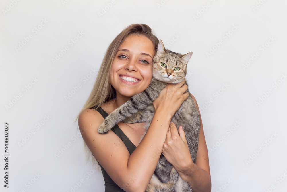 © Марина Демешко - A young beautiful smiling blonde woman holds young Tabby cat in her hands isolated on a white background. Good friends. Friendship of a pet and its owner. Cuddles © Марина Демешко - A young beautiful smiling blonde woman holds young Tabby cat in her hands isolated on a white background. Good friends. Friendship of a pet and its owner. Cuddles