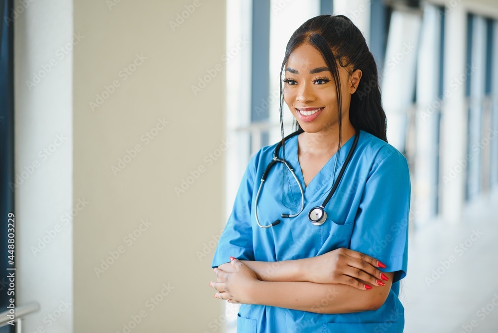 medicine, profession and healthcare concept - happy smiling african american female doctor with stethoscope over hospital background medicine, profession and healthcare concept - happy smiling african american female doctor with stethoscope over hospital background