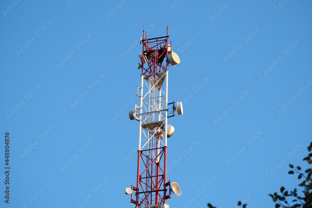Telecommunications tower with a 5G cellular network antenna on a blue sky background. Telecommunications tower with a 5G cellular network antenna on a blue sky background.