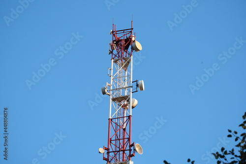 Telecommunications tower with a 5G cellular network antenna on a blue sky background.