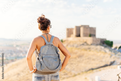 Woman in summer clothes standing and looking at a medieval castle