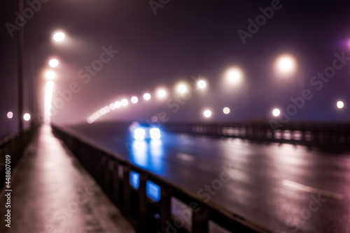 The bright lights of the city at night, the car goes over the road bridge. Defocused image