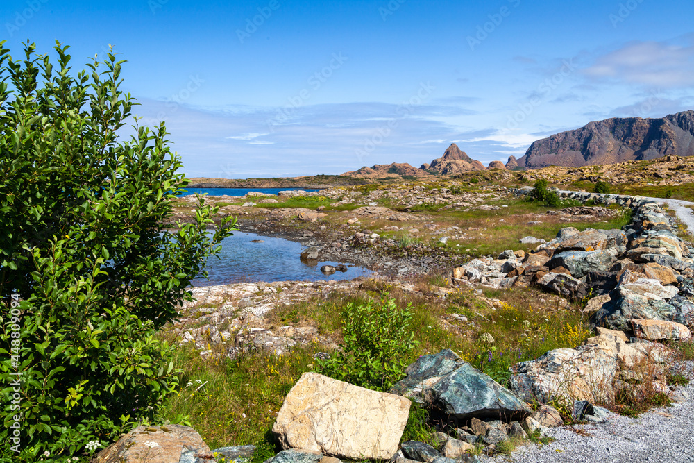 Leka island coastal shoreline with Heilhornet mountain on the horizon under blue clear skies. Trondelag county, Norway