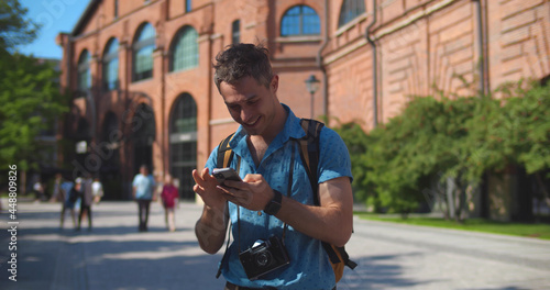 Caucasian tourist man smiling happy using smartphone at summer city abroad