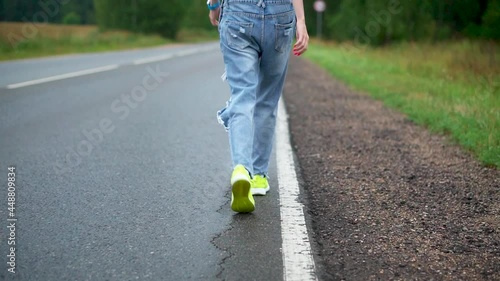 A girl walks along the highway and tries to stop a passing car