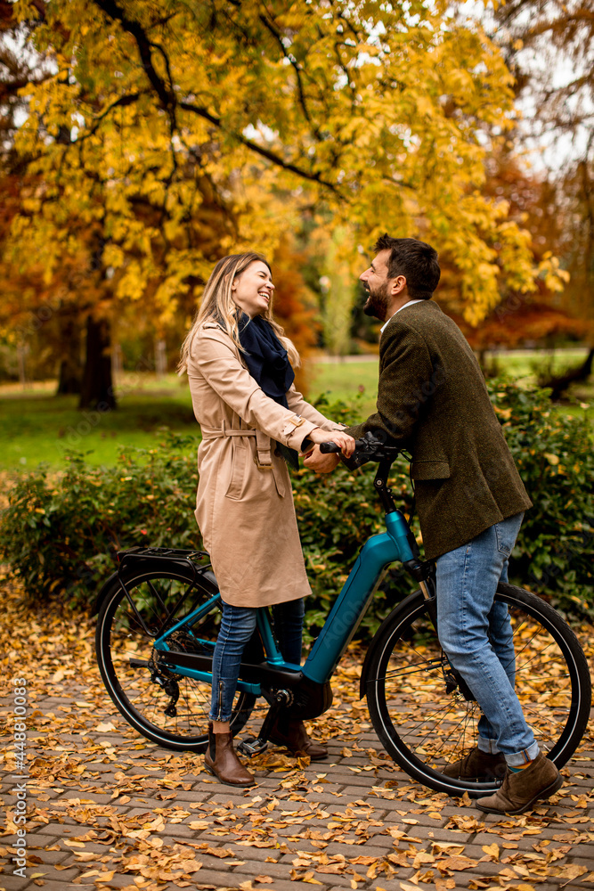Obraz premium Young couple in the autumn park with electrical bicycle