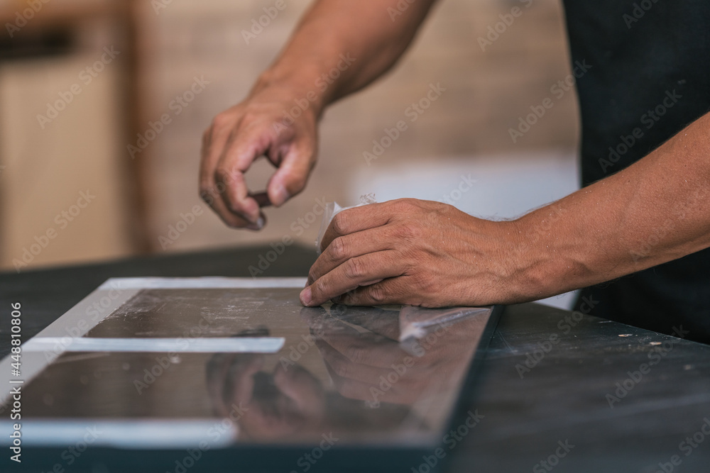Hands removing the protective tape from a piece of furniture Hands removing the protective tape from a piece of furniture