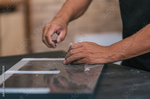 Hands removing the protective tape from a piece of furniture