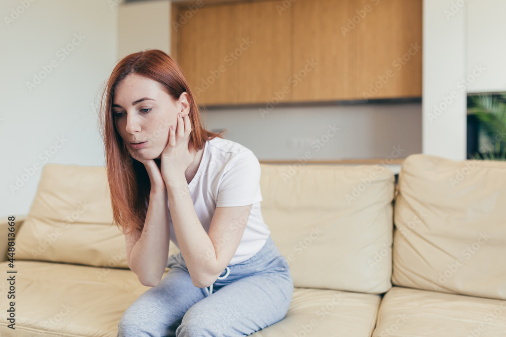 Young woman alone at home with a panic attack shortness of breath, trembling, numbness, loss of consciousness. Front view of a female suffering an anxiety sitting on a couch. chest pain, fear symptom Young woman alone at home with a panic attack shortness of breath, trembling, numbness, loss of consciousness. Front view of a female suffering an anxiety sitting on a couch. chest pain, fear symptom