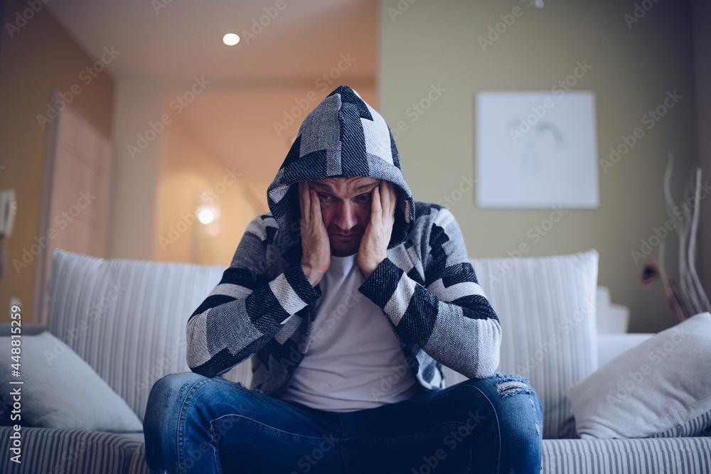 Depressed hadsome man sitting on sofa in the living room.