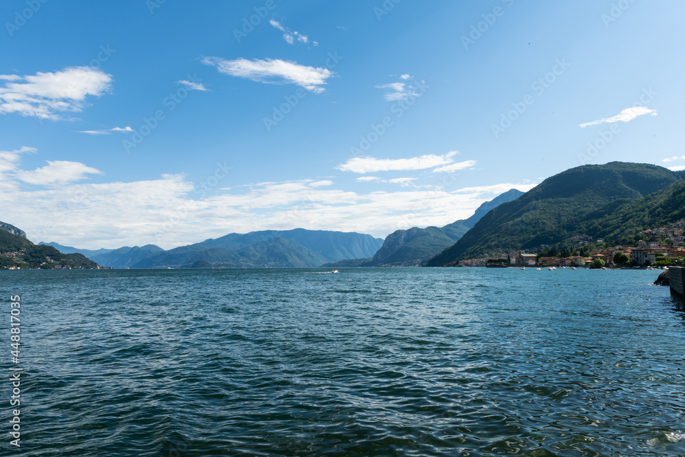 View over the beautiful, gorgeous lake Como seen from the small village of Santa Maria Rezzonico. It is a beautiful sunny summer day, with blue sky and a few clouds. There are boats on the lake.