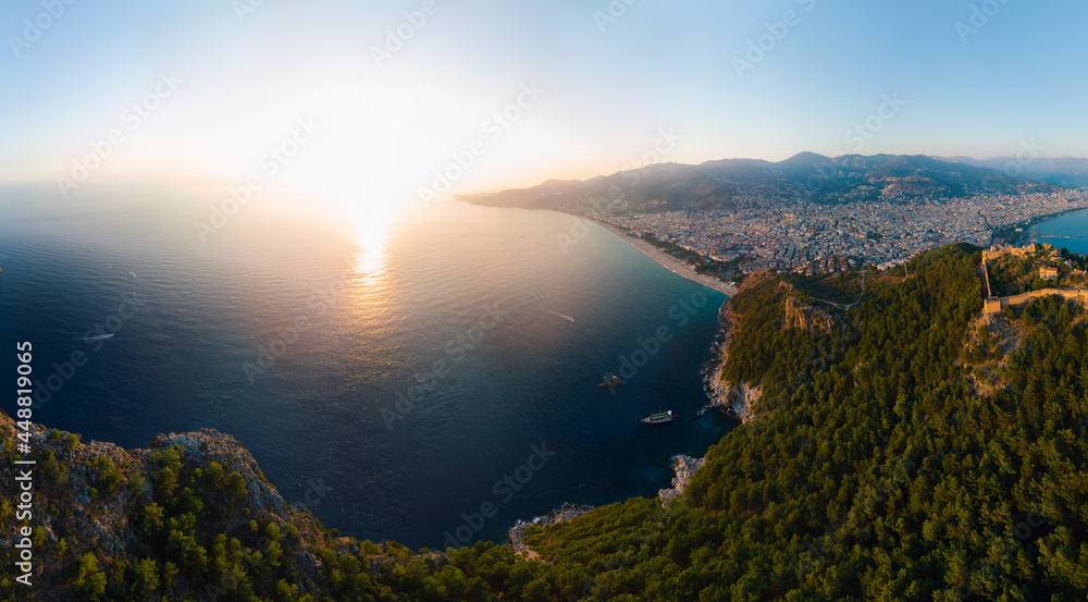 Large panorama. Wide aerial view from Kalesi Castle peninsula. Alanya, southern coast of Turkey, Summer sunset. Travel and vacation. Ships and boats in the sea. Cleopatra beach and lake. Copy space