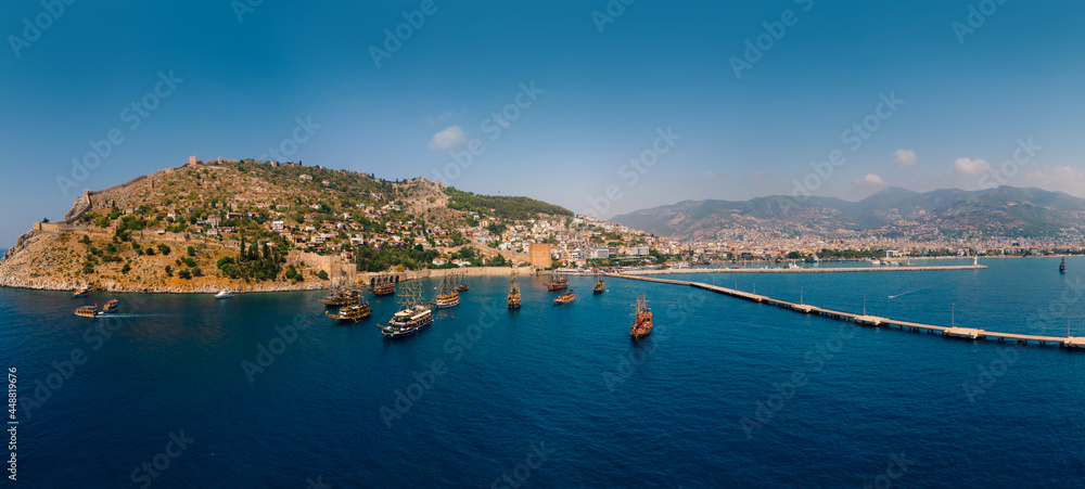 Aerial wide panoramic view of Alanya in southern coast of Turkey, Summer morning day. Travel and vacation. Kalesi Castle. Ships and boats. Show program and entertainment for tourists, swimming