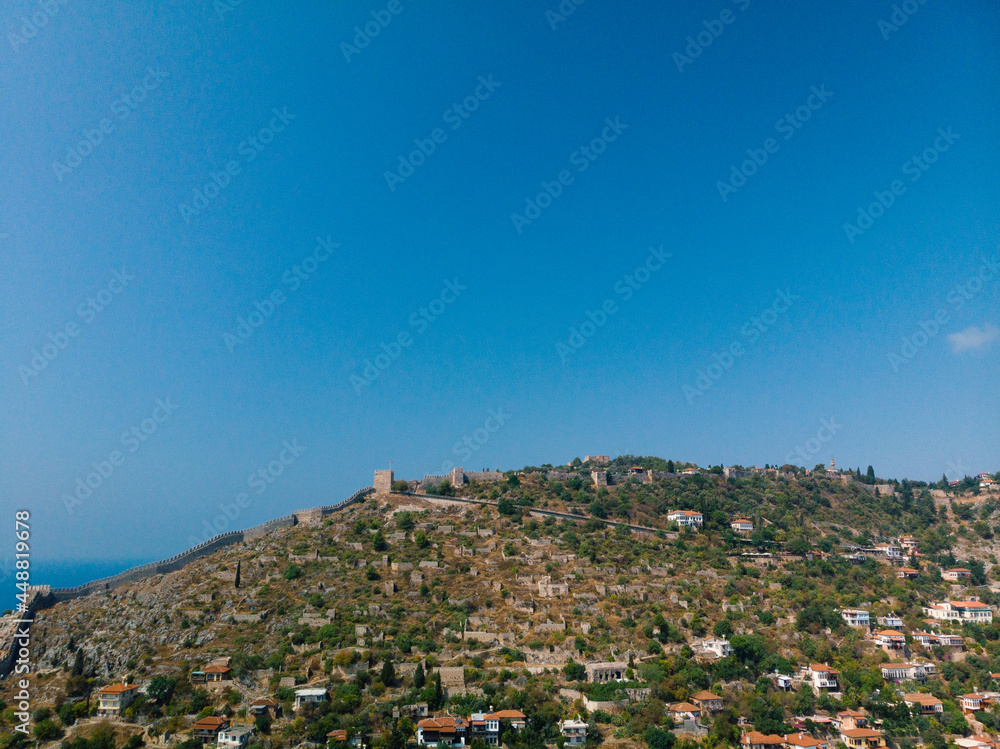 Fototapeta premium Aerial view resort city Alanya in southern coast of Turkey, Summer day. Travel and vacation. Kalesi Castle. Mountain. Ships and boats in the mediterranean