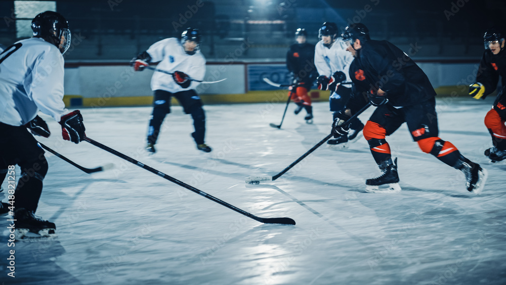 Obraz premium Ice Hockey Arena: Professional Forward Player Breaks Defense, Prepairing to Shot Puck with Stick to Score Goal. Two Competitive Teams Play Intense Game.