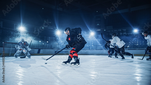 Ice Hockey Rink: Professional Forward Player Breaks Defense, Prepairing to Shot Puck with Stick to Score Goal. Two Competitive Teams Play Intense Game. photo