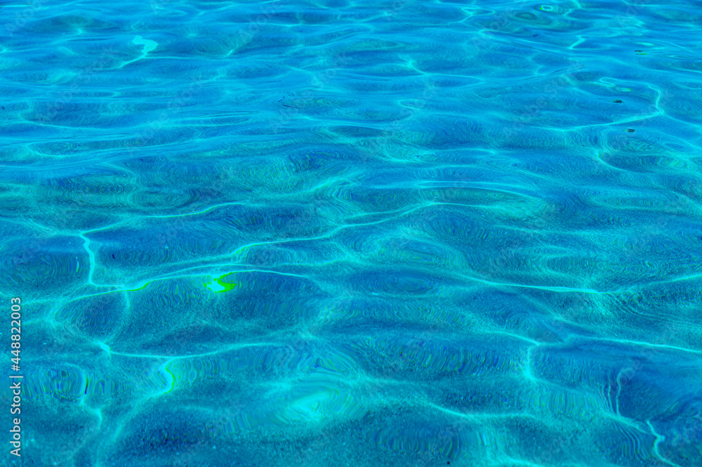 Marine background. Transparent turquoise-blue sea water against the background of white sand below, top view. Sun glare on the surface. High quality photo Marine background. Transparent turquoise-blue sea water against the background of white sand below, top view. Sun glare on the surface. High quality photo