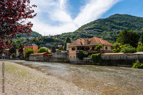 Stock photo of river Pioverna in the city of Bellano, in Lake Como, Lombardy, Italy. Picture taken upstream. There are houses and hills behind the river. It is a beautiful sunny summer day photo