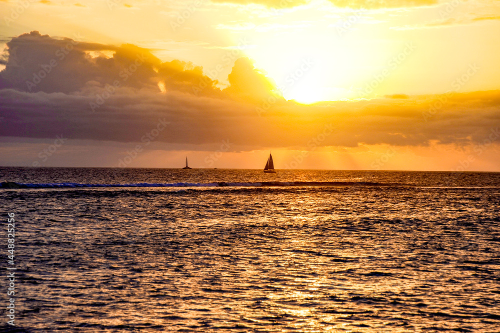Sailboat silhouette in the setting sun over the ocean on the island of Maui, Hawaii.  