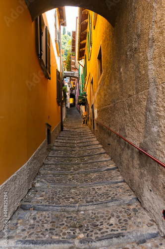 Very narrow alley in Varenna  lake Como  Lombardy  Italy. Narrow alley between the residential buildings in Varenna by Como lake  Lombardy  Italy. Just a little sun comes down in the alley