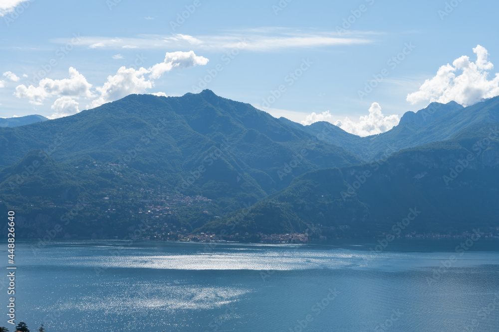 Beautiful view over the stunning lake Como in Lombardy, Italy. It is a very nice sunny summer day, with blue sky and a few white clouds. View is over the city of Menaggio.