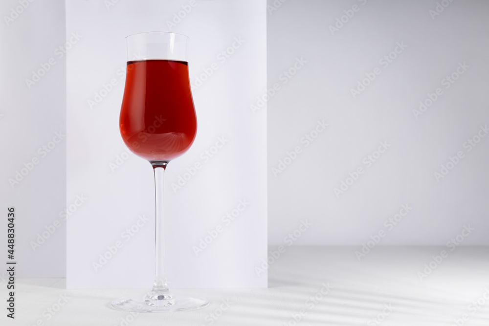 Red wine in elegant glass in sunlight with shadow in soft light white abstract minimal interior with rectangle space. Red wine in elegant glass in sunlight with shadow in soft light white abstract minimal interior with rectangle space.