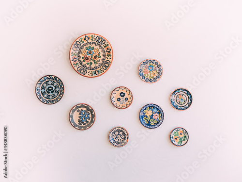 Beautifully designed ceramic colorful plates hanging on the white wall as decorations