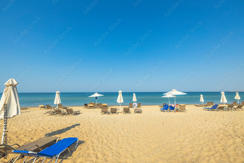 Obraz premium Beautiful landscape view of empty sunbeds and umbrellas on sand beach. Greece.