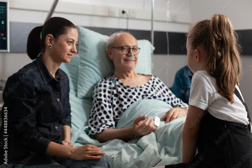 Elderly sick old man resting in bed talking with caring granddaughter after medical expertise hospital ward. Grandfather enjoying spending time with child during clinical surgery. Healthcare treatment Elderly sick old man resting in bed talking with caring granddaughter after medical expertise hospital ward. Grandfather enjoying spending time with child during clinical surgery. Healthcare treatment