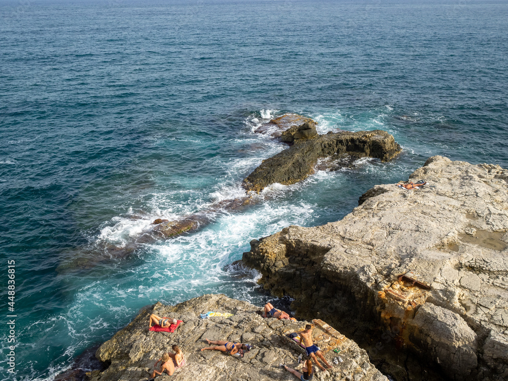 Sunbathing on the rocks by the Mediterranean Sea in Siracusa