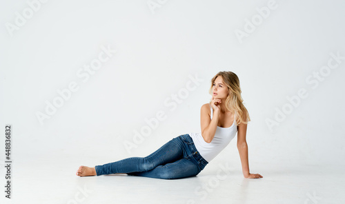 pretty blonde in a white t-shirt in jeans lies on the floor posing