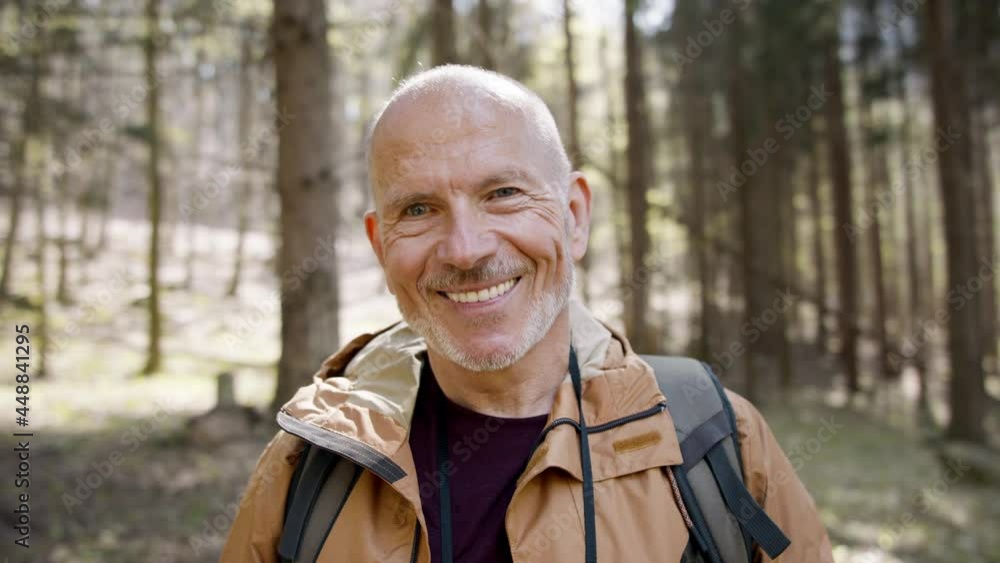 Senior man hiker outdoors walking in forest in nature, standing and looking at camera. Senior man hiker outdoors walking in forest in nature, standing and looking at camera.